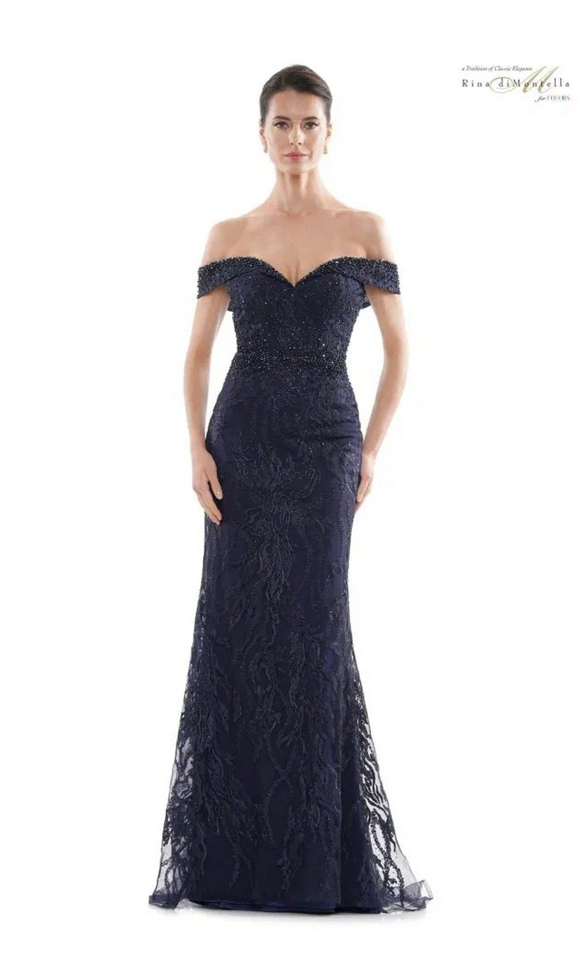 A woman wears the Rina Di Montella RD2713, a navy long formal dress featuring off-the-shoulder styling, intricate lace, and beaded embellishments.